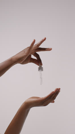 Close-Up-Of-Woman-Squeezing-Dropper-From-Bottle-Of-Beauty-Product-On-White-Background-3